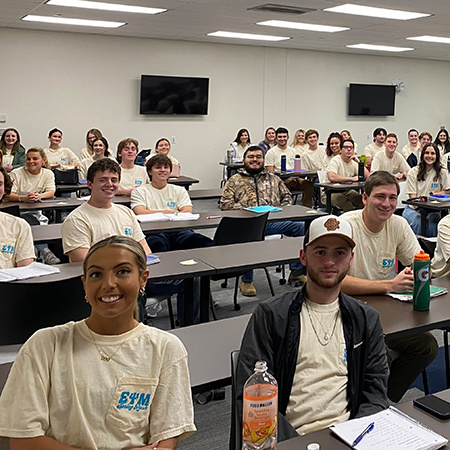 Members of Sigma Psi Mu, a co-ed professional fraternity for sport and entertainment management majors, smile for the camera at a meeting.