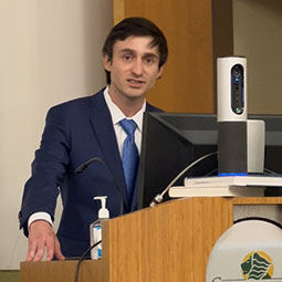 man speaking at a podium with a blue suit on