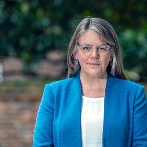 Lori Ziolkowski, wearing a blue jacket, stands in front of a brick wall 