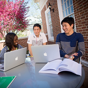 Three students smile while sitting at a table.