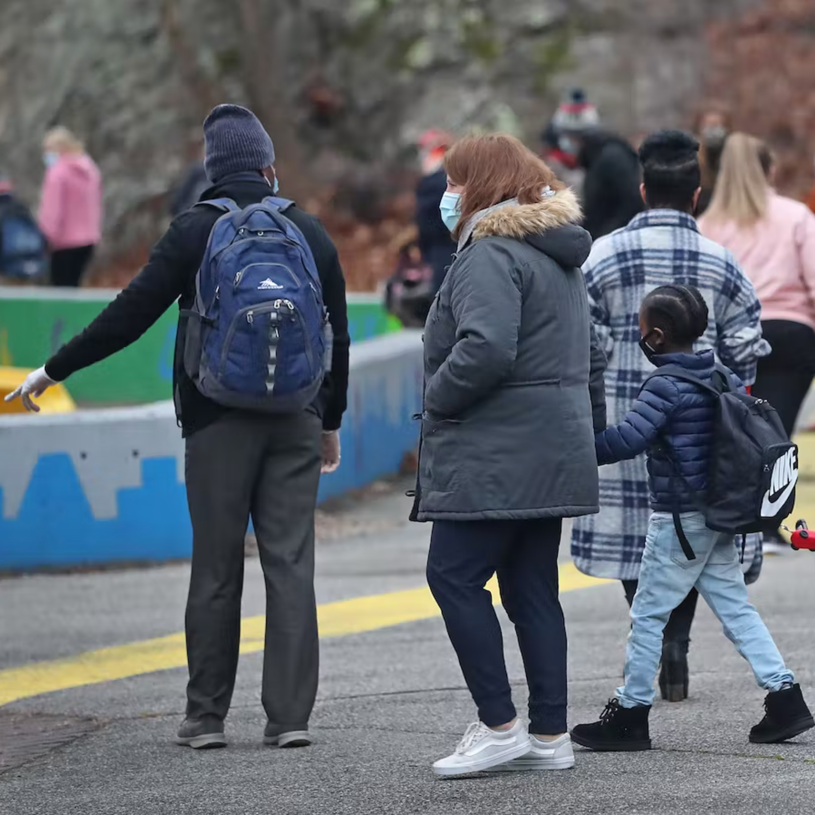 Parents and a child walk into school wearing masks